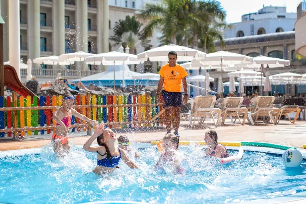 Piscina con ni&ntilde;os jugando y un socorrista en un hotel, salpicaduras de agua