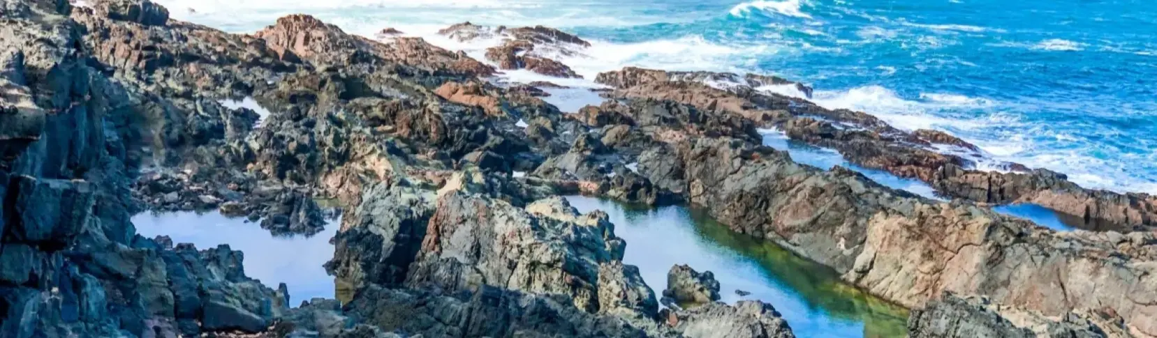 Acantilados rocosos y olas del oc&eacute;ano, con bah&iacute;a y costa escarpada.