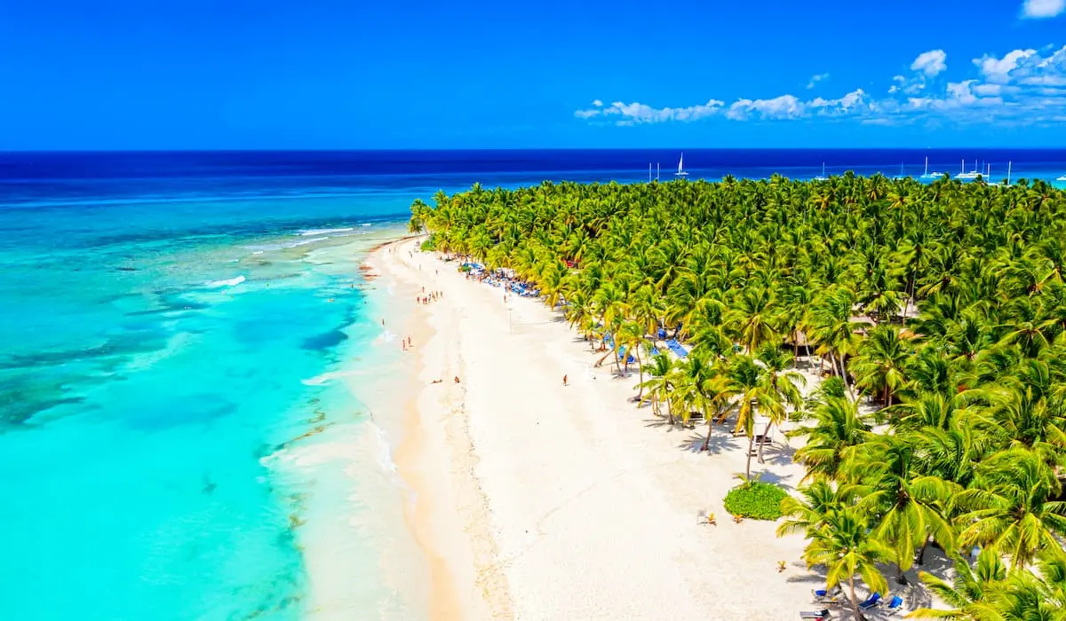 Playa tropical con palmeras y aguas turquesa bajo un cielo azul con nubes