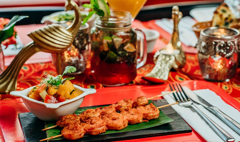 Pinchos a la parrilla con salsa y guarnici&oacute;n en mesa con t&eacute; marroqu&iacute;