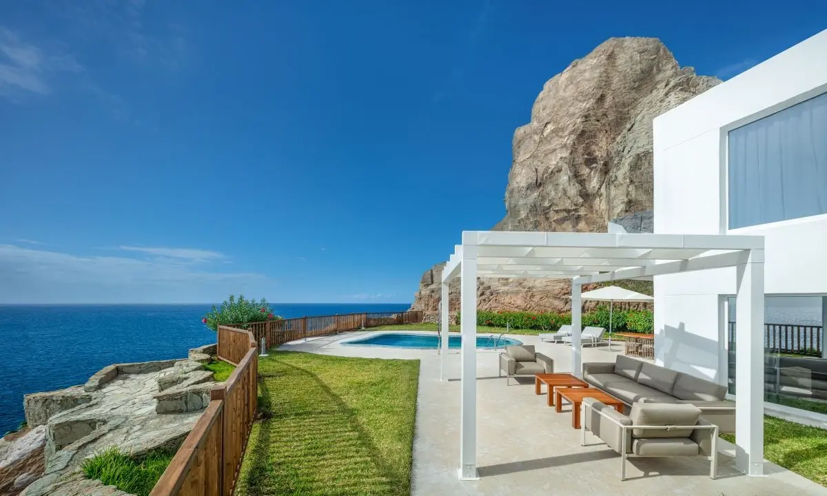 Panoramic terrace of a luxury suite with private pool and a garden with a sofa and table area beneath a pergola