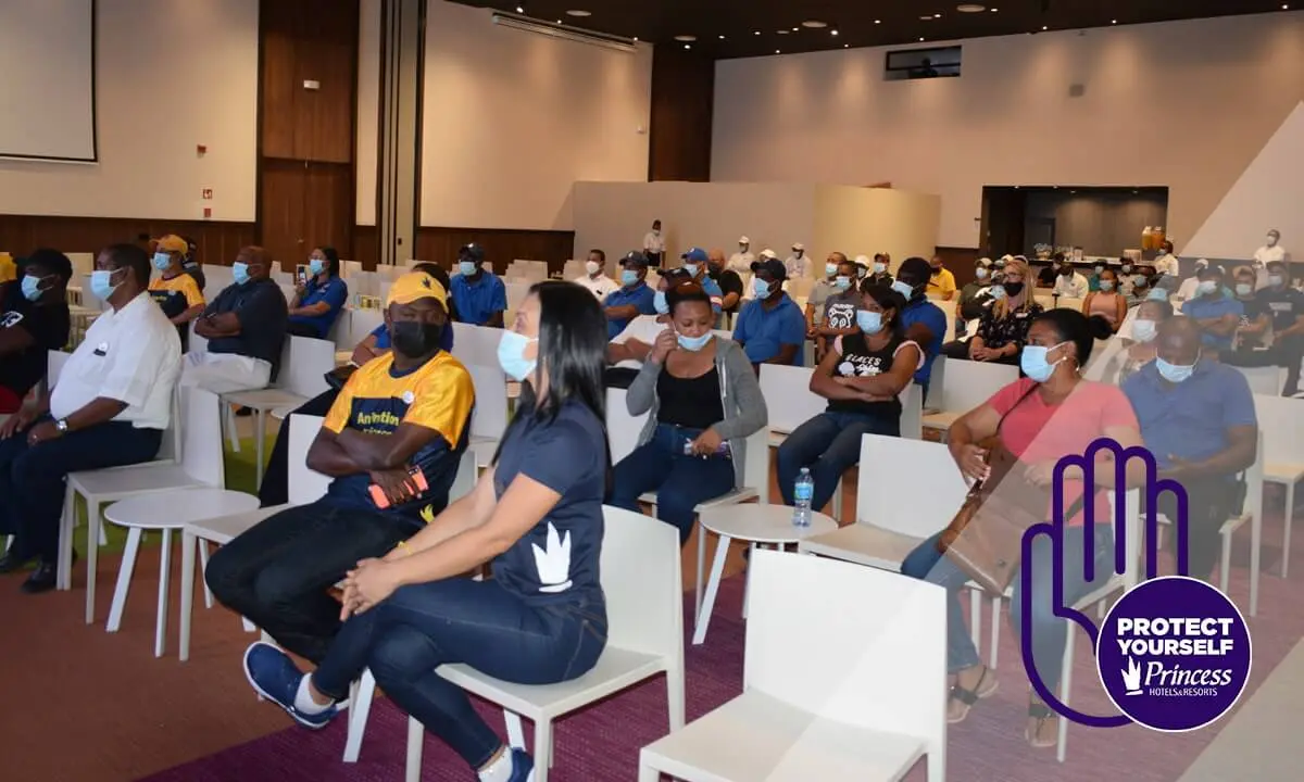 Personas sentadas en conferencia con cubrebocas en una sala.