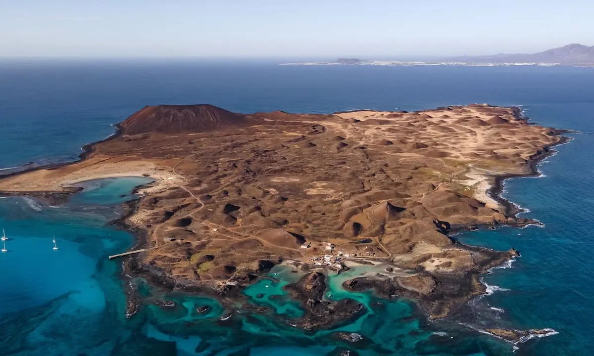 Vista a&eacute;rea de una isla des&eacute;rtica con calas de aguas turquesas y playas.
