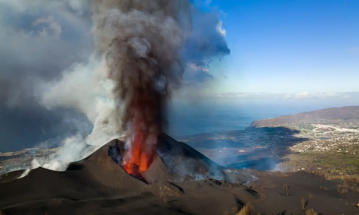 Erupci&oacute;n volc&aacute;nica con lava y humo sobre el paisaje costero