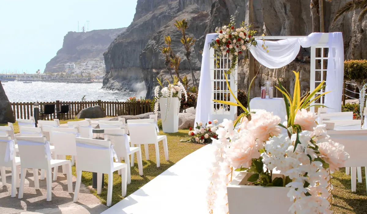 Bodas al aire libre con sillas blancas y decoraci&oacute;n floral frente al mar