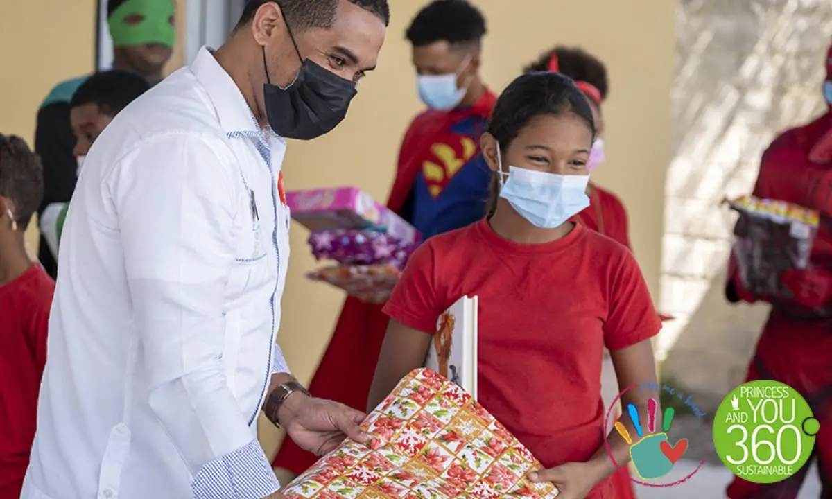 M&eacute;dico entrega regalos a una ni&ntilde;a con mascarilla en un evento solidario