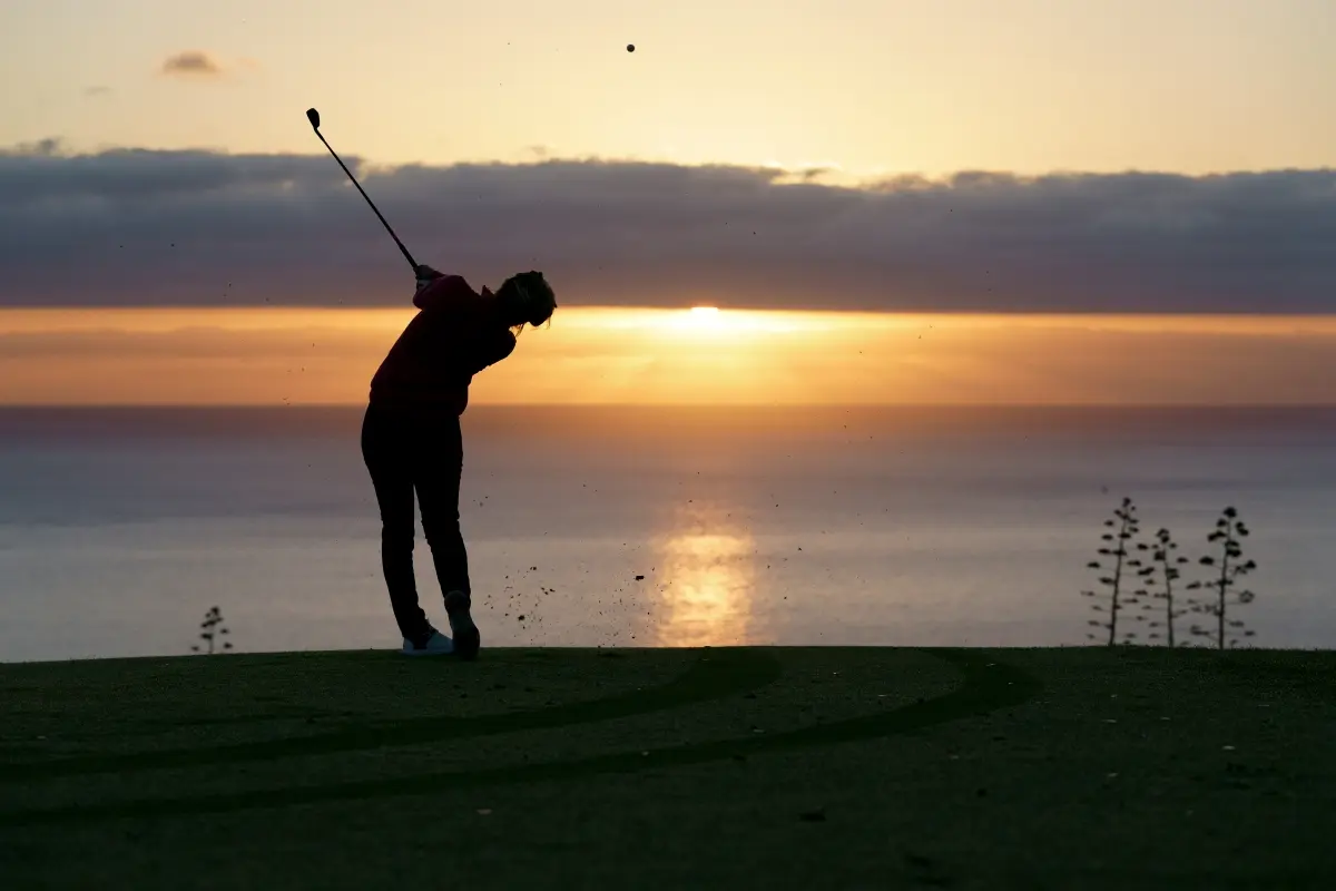 Jugador de golf con silueta en el atardecer sobre el campo