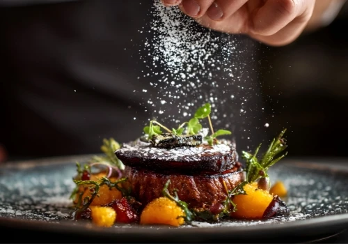 Cocinero espolvorea sal sobre un plato con verduras y vegetales asados