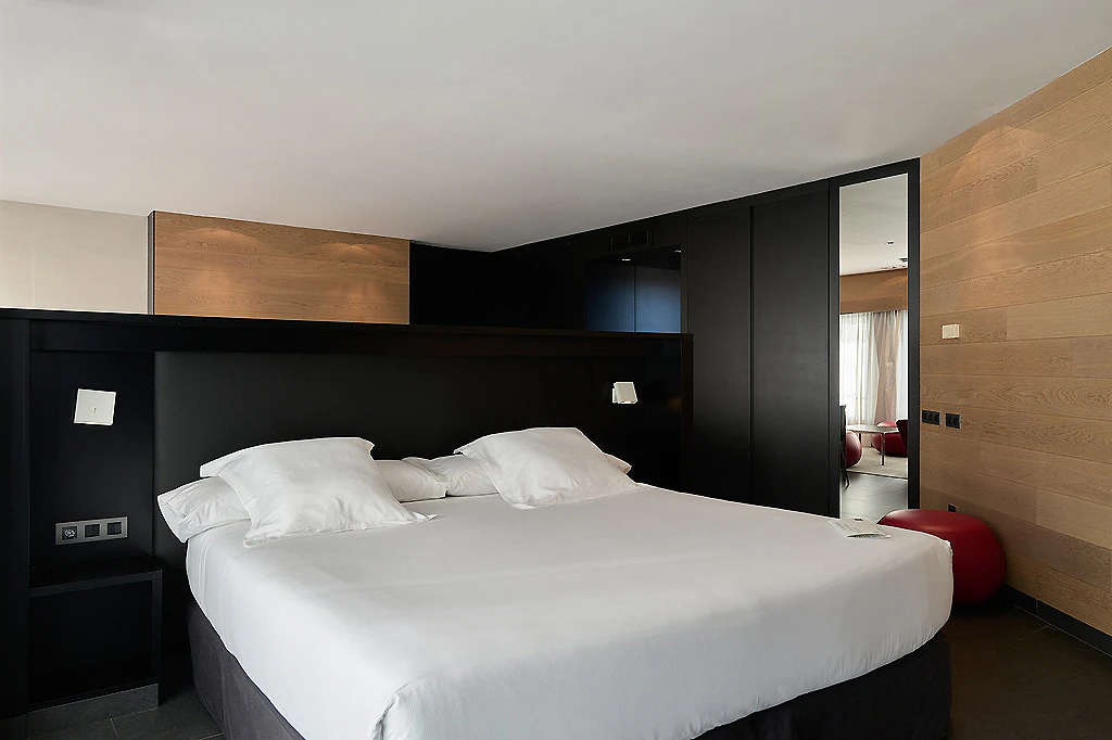 Dormitorio moderno con cama blanca y armarios negros, estilo minimalista