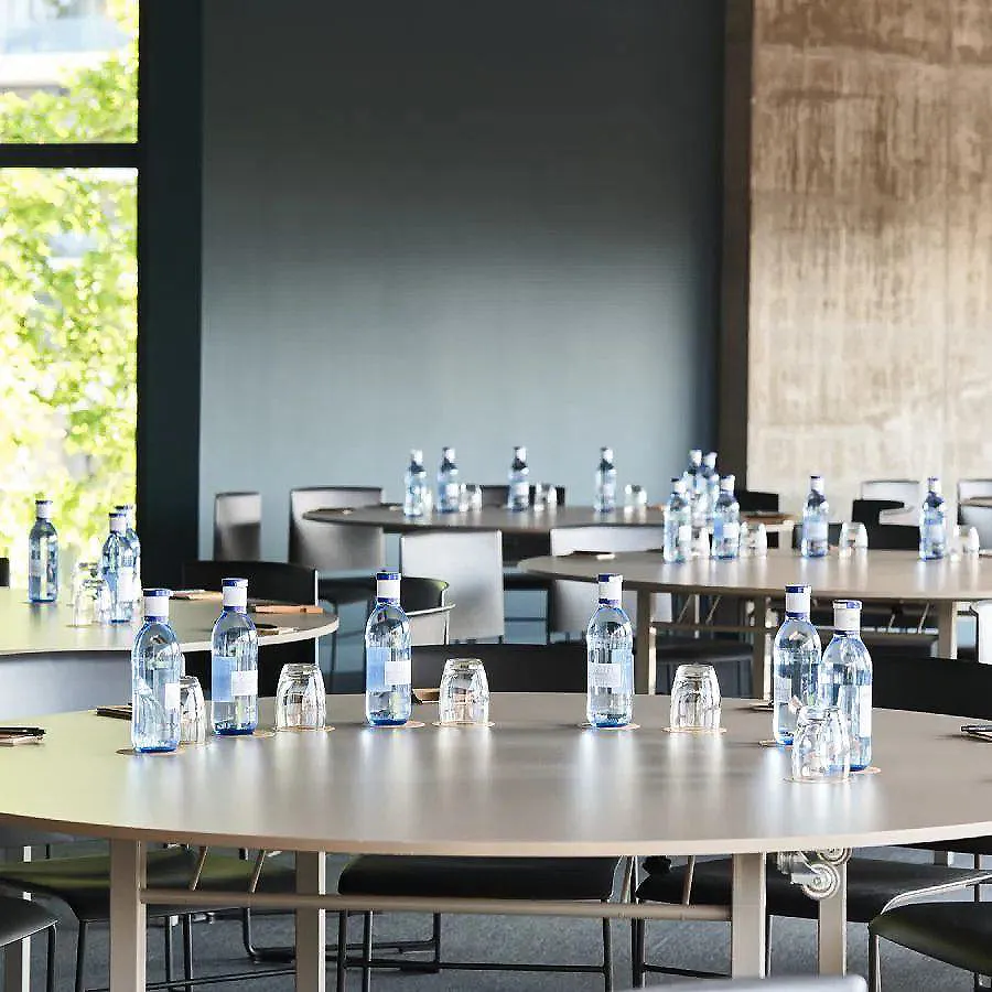 Mesa con botellas de agua y vasos, en sala de eventos.