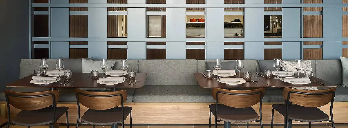 Mesa con vajilla y copas en un comedor moderno con pared geom&eacute;trica.