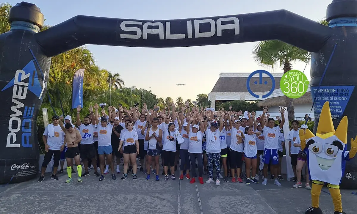 Equipo de j&oacute;venes saludando bajo arco inflable &ldquo;SALIDA&rdquo; en evento deportivo.