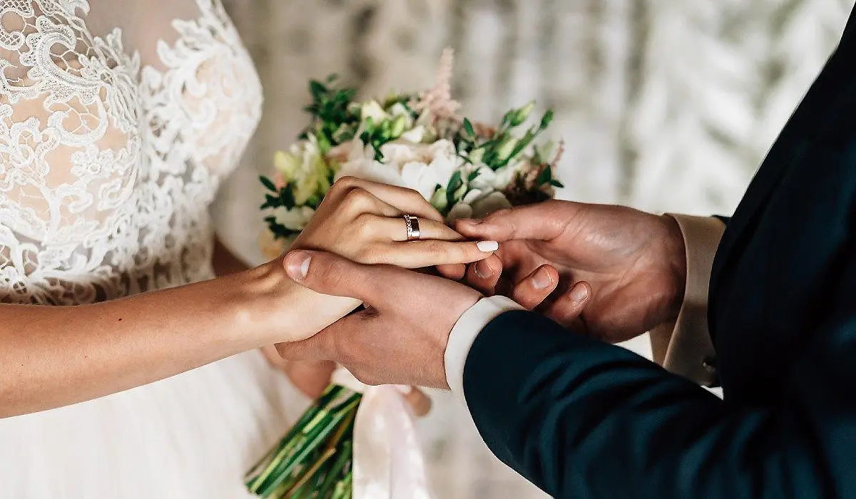 Manos de la pareja se sujetan mientras intercambian anillos de boda