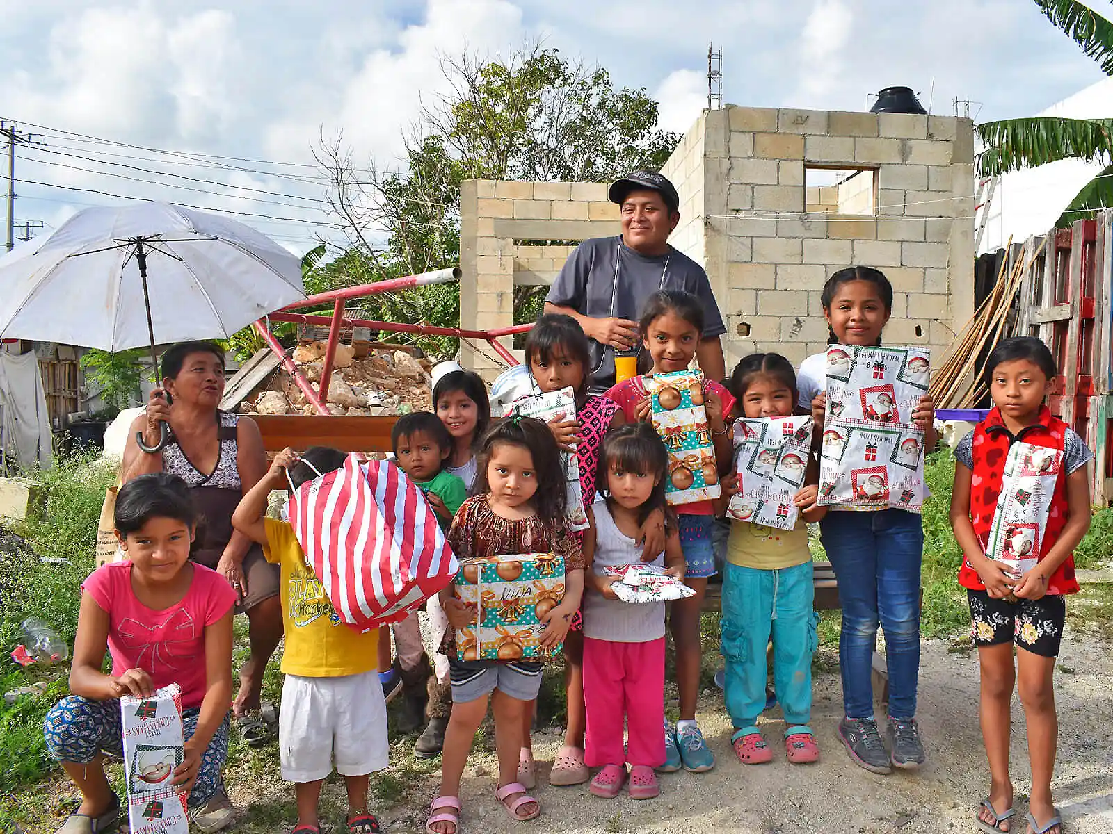 Ni&ntilde;os y un adulto posan sonriendo con bolsas de regalo en el patio.