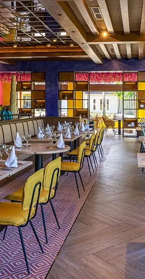 Comedor con mesas, sillas amarillas y largas l&aacute;mparas, interiores modernos