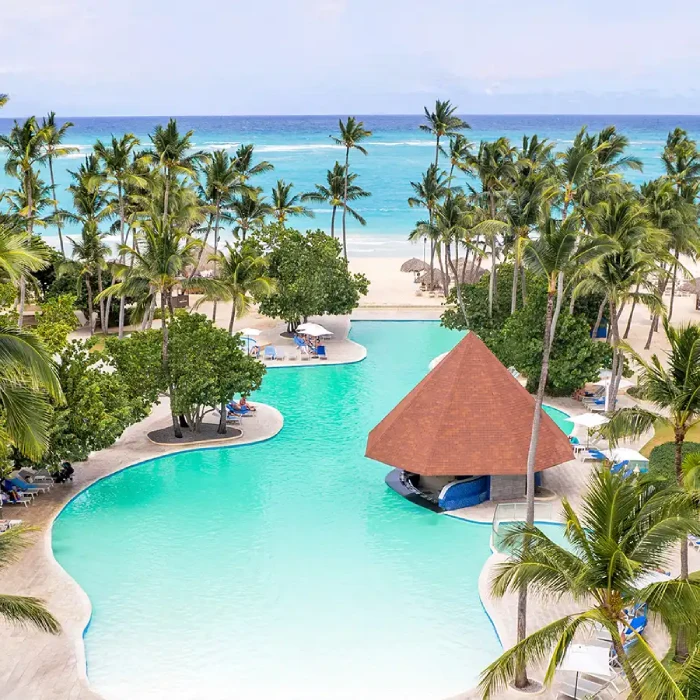 Piscina tropical con palmeras y vista al mar.