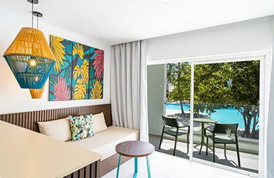 Sala moderna con mesa, sof&aacute; y terraza con vista al jard&iacute;n y piscina