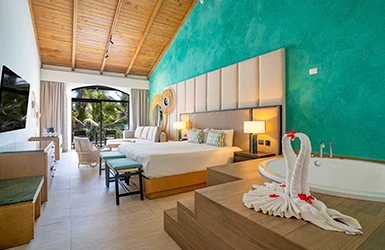 Dormitorio moderno con cama, jacuzzi y decoraci&oacute;n tropical en suite.