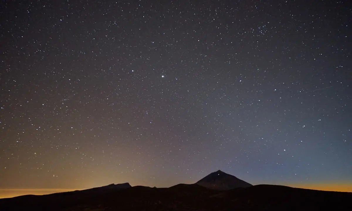 Cielo nocturno estrellado con la silueta de monta&ntilde;as al amanecer