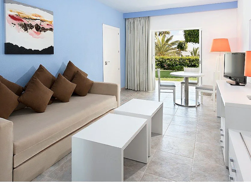 Sala luminosa con sof&aacute;, mesa blanca y vista al jard&iacute;n por la ventana