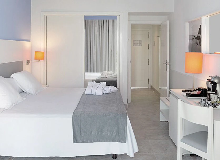 Habitaci&oacute;n de hotel moderna con cama, l&aacute;mparas y cafetera en la mesa