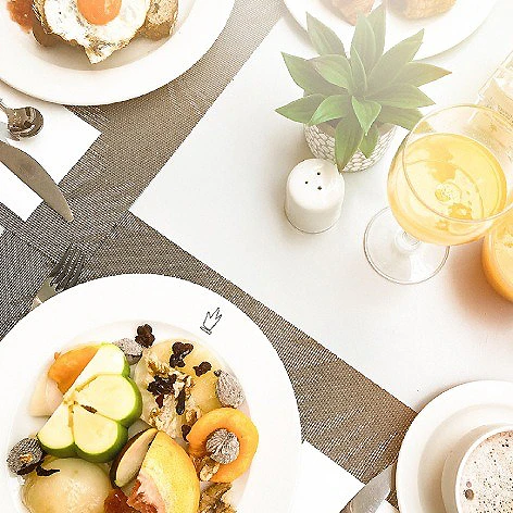 Comida casera en platos, tazas y plantas en una mesa con mantel beige