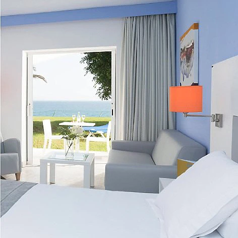 Habitaci&oacute;n de hotel con cama, sof&aacute; y vista al mar por la ventana.