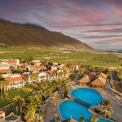 Vista a&eacute;rea de un resort con piscina y monta&ntilde;as al atardecer.
