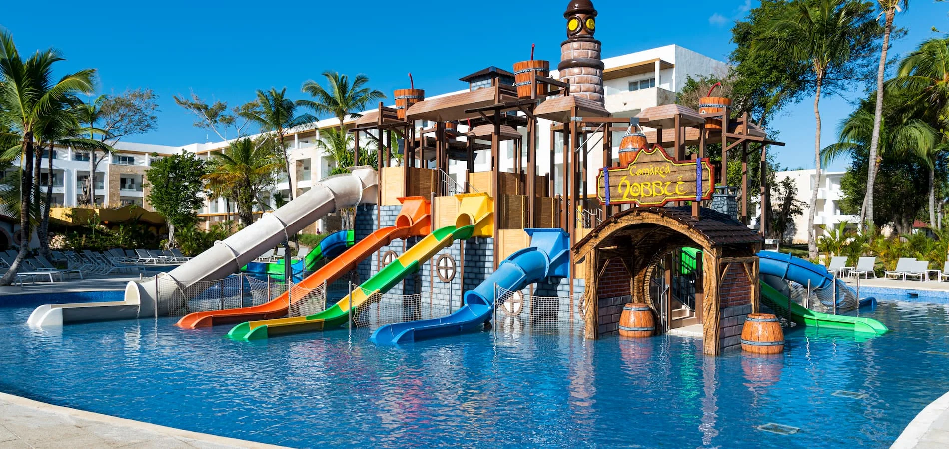 Piscina hotelera con toboganes de colores y torre con letrero &ldquo;Comarca Lobaxt&rdquo;