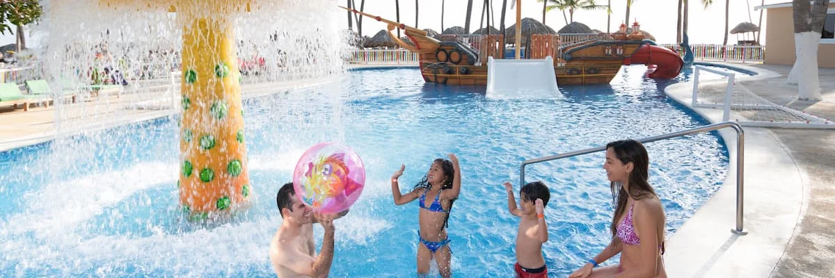 Familia en una piscina con fuente y barco de juguete en el fondo