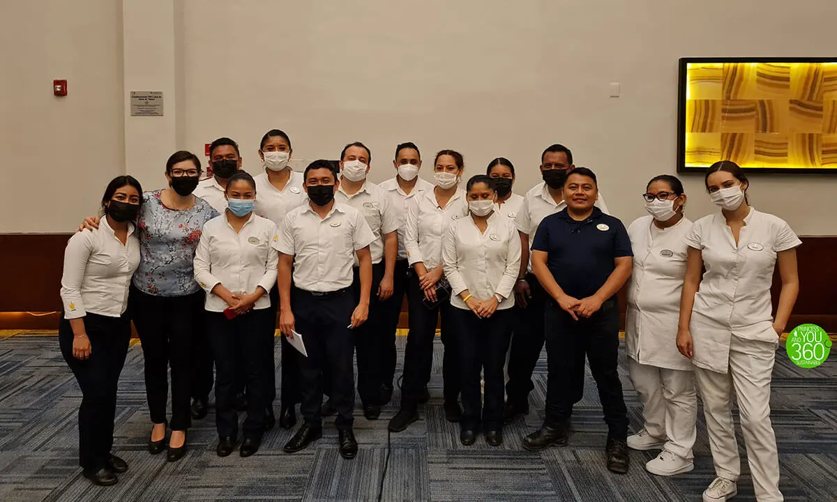 Equipo de personas con cubrebocas en una foto grupal en oficina.