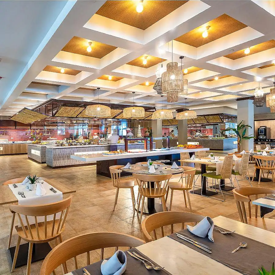 Comedor de hotel moderno con mesas, sillas y l&aacute;mparas colgantes.