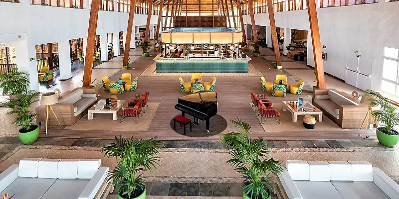Patio interior con piscina, camastros y piano en un resort.