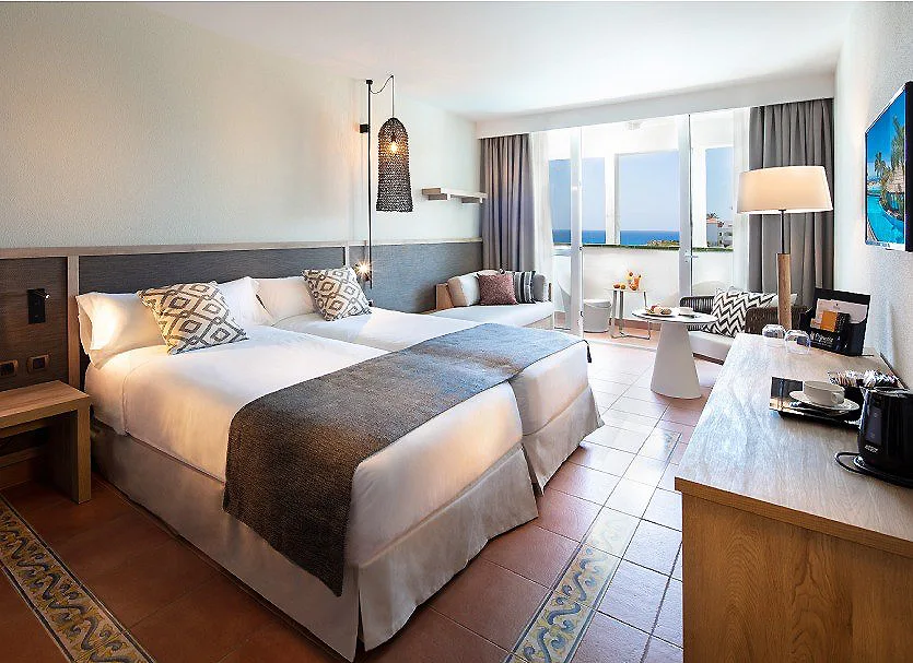 Habitaci&oacute;n de hotel moderna con cama doble, mesa y vista al mar