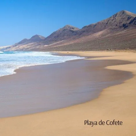 Playa de Cofete con arena dorada, olas y monta&ntilde;as al fondo
