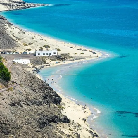 Playa turquesa con acantilados y casas blancas junto a la costa