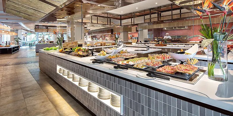 Buffet de desayuno con platos y mesas en un comedor luminoso de hotel