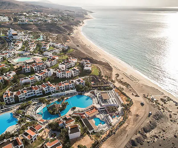 Vista a&eacute;rea de playa y complejo tur&iacute;stico con piscinas junto al mar