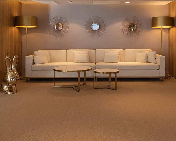 Sala de estar moderna con sof&aacute; blanco, mesas y l&aacute;mparas en pared beige.