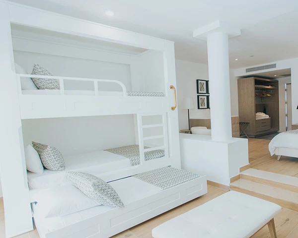 Cama nido blanca en habitaci&oacute;n moderna con muebles y luz natural