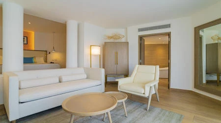 Sala de estar moderna con sof&aacute; blanco, sill&oacute;n y mesa redonda.