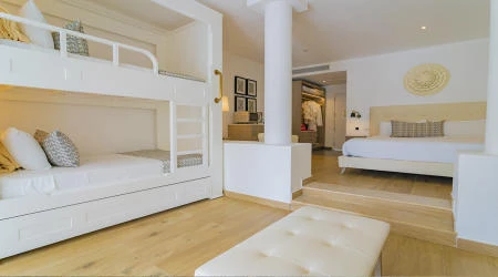 Dormitorio luminoso con cama blanca, sala y sof&aacute;, estilo moderno.