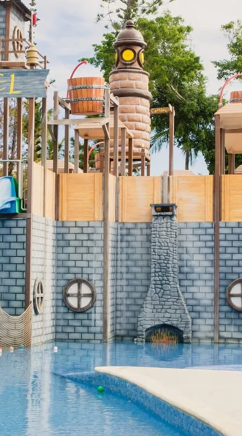 Tobog&aacute;n de piedra con salida de agua en piscina, parque acu&aacute;tico al aire libre