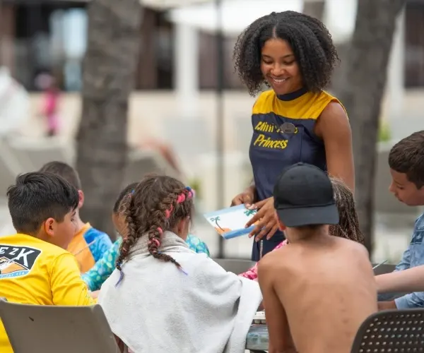 Voluntaria reparte materiales a ni&ntilde;os en una actividad al aire libre.