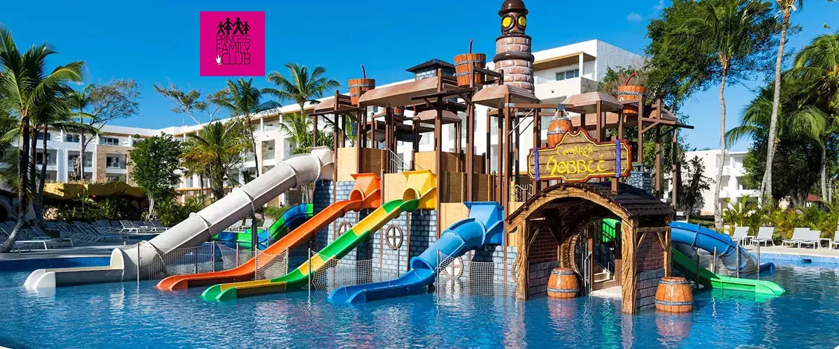 Piscina con toboganes de colores y puente decorado en resort tropical.
