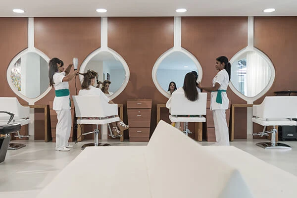 Personas trabajando en un sal&oacute;n de est&eacute;tica con espejos circulares.