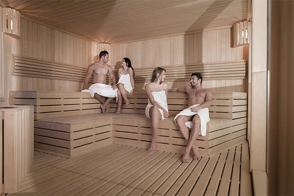 Personas relaj&aacute;ndose en una sauna de vapor con paredes de madera