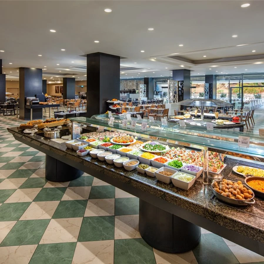 Buffet de ensaladas y platos en hotel, con mesa de vidrio y luces interiores