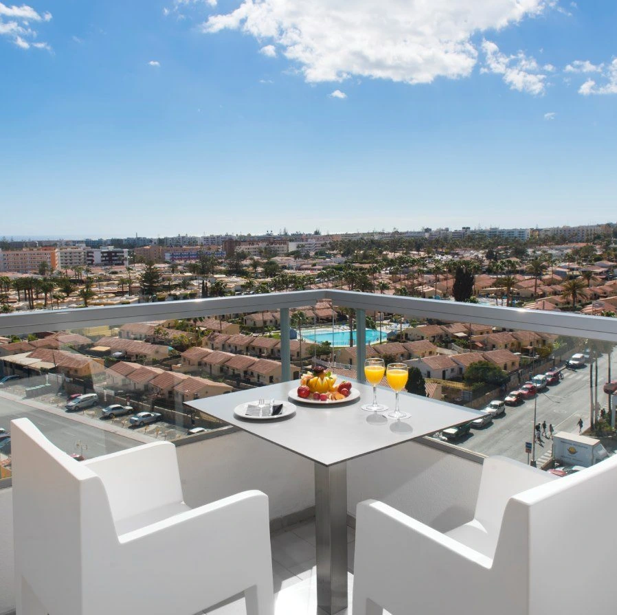 Terraza con mesa y copas de jugo, vista panor&aacute;mica de la ciudad y playa