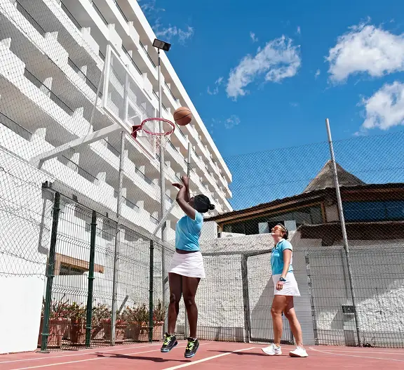 Personas jugando baloncesto en una cancha al aire libre con cielo azul